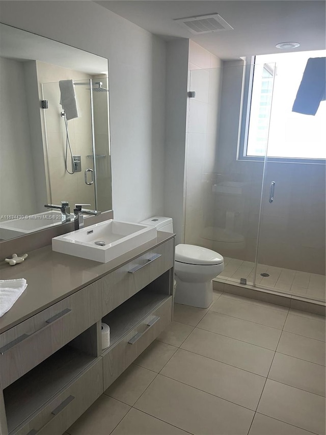 bathroom with toilet, double sink vanity, walk in shower, and tile patterned flooring