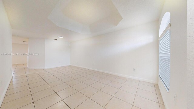 spare room featuring light tile patterned floors and a tray ceiling