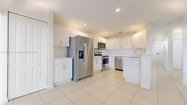 kitchen with stainless steel appliances, light tile patterned flooring, sink, and white cabinets