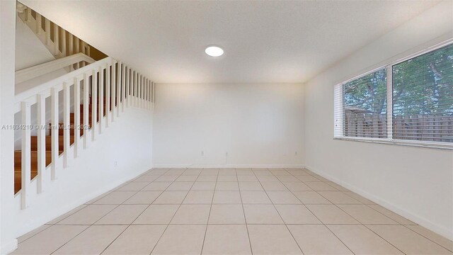 spare room with a textured ceiling and light tile patterned floors