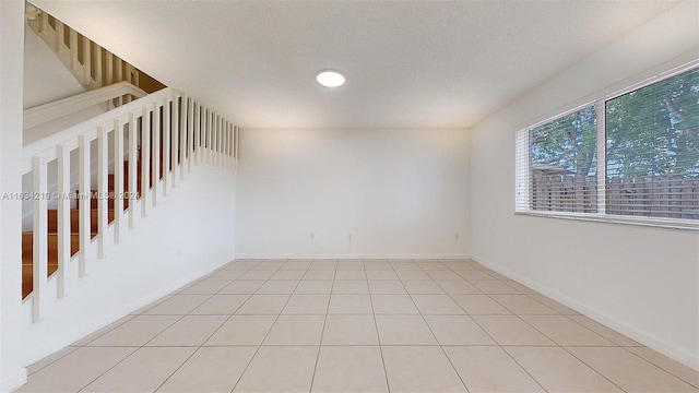 unfurnished room featuring a textured ceiling and light tile patterned floors