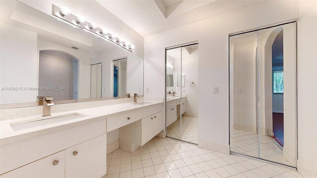 bathroom with tile patterned floors, a textured ceiling, and dual bowl vanity