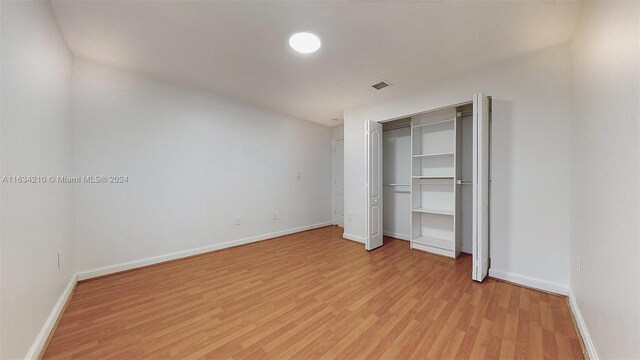 unfurnished bedroom with light hardwood / wood-style flooring and a closet