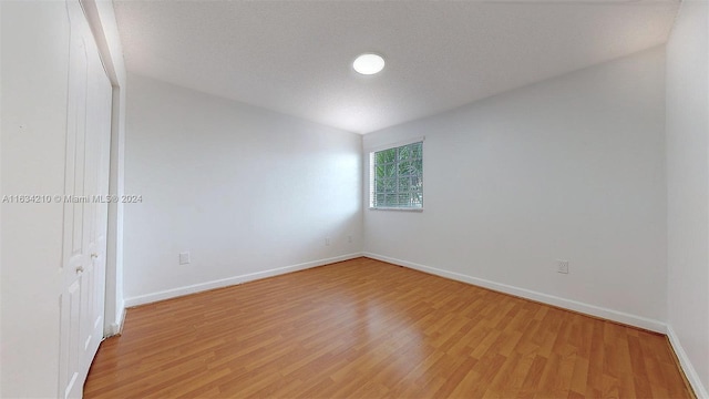 empty room with light hardwood / wood-style floors and a textured ceiling