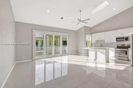 kitchen with backsplash, open floor plan, white cabinetry, stainless steel appliances, and light countertops