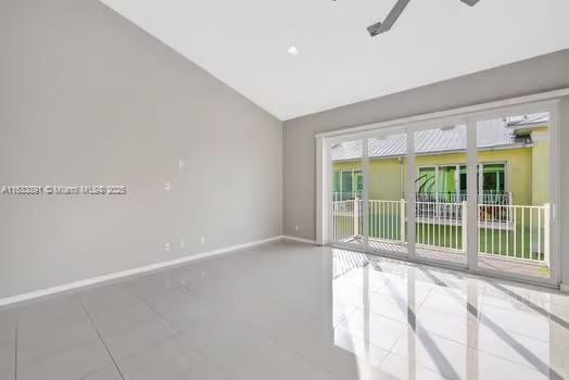 tiled empty room with baseboards and lofted ceiling