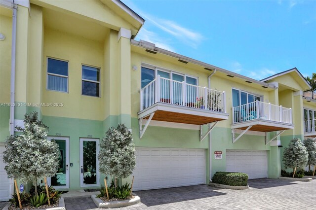 view of property featuring decorative driveway, an attached garage, and stucco siding