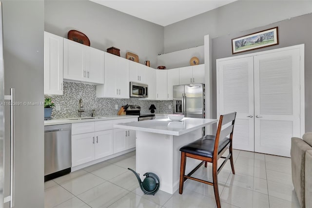 kitchen with white cabinetry, stainless steel appliances, a kitchen breakfast bar, and a center island