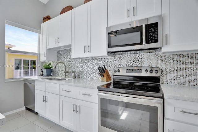 kitchen with tasteful backsplash, light tile patterned floors, white cabinets, stainless steel appliances, and a sink