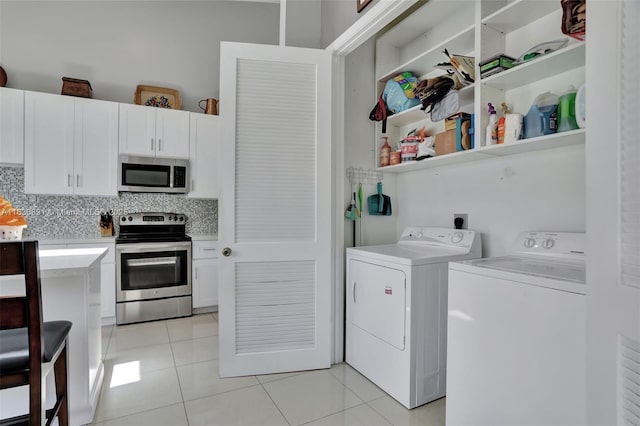 washroom featuring washing machine and clothes dryer, laundry area, and light tile patterned flooring