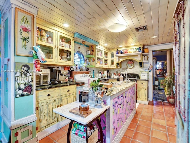 kitchen with wood ceiling, sink, light tile patterned floors, and an island with sink