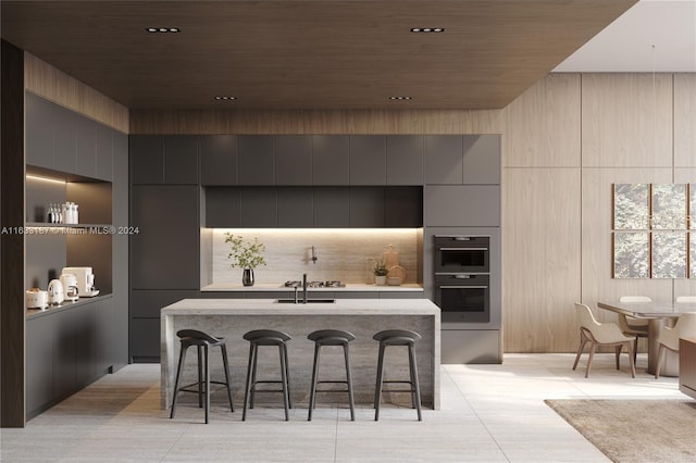 kitchen featuring gray cabinetry, wood ceiling, sink, a breakfast bar area, and double oven