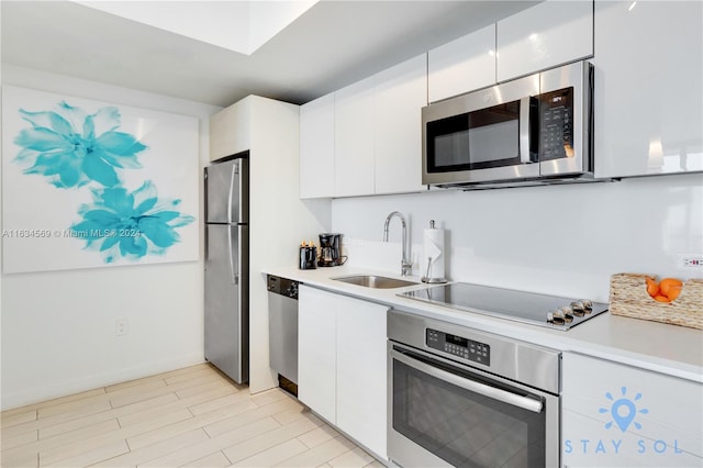 kitchen with appliances with stainless steel finishes, white cabinetry, light tile patterned floors, and sink