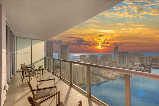 balcony at dusk featuring a water view