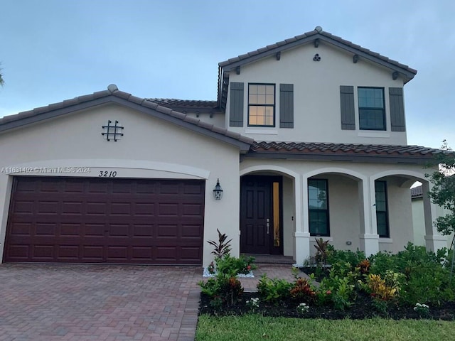 mediterranean / spanish house with covered porch and a garage