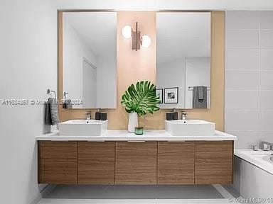 bathroom with double vanity and a bath