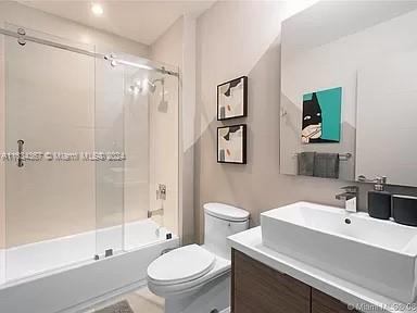 full bathroom with toilet, shower / bath combination with glass door, and vanity