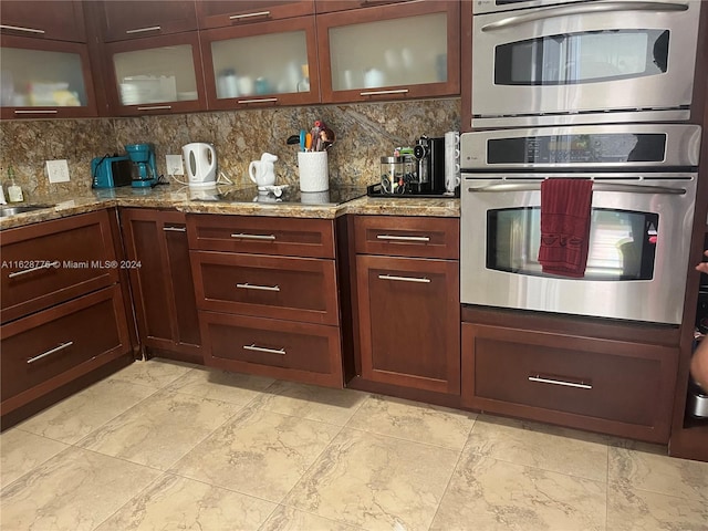 kitchen featuring double oven, light tile patterned floors, tasteful backsplash, and light stone countertops