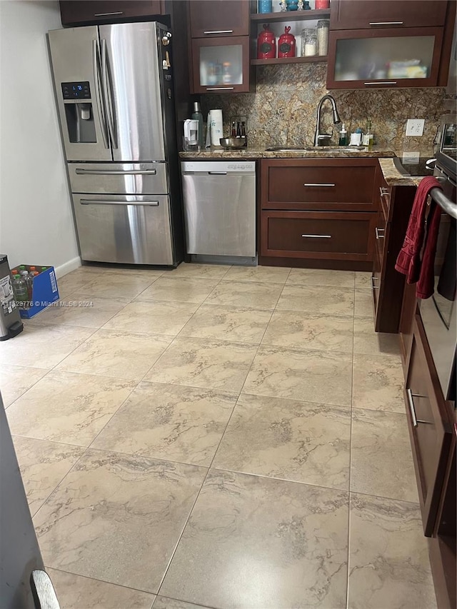 kitchen with light tile patterned floors, dark stone counters, backsplash, stainless steel appliances, and sink