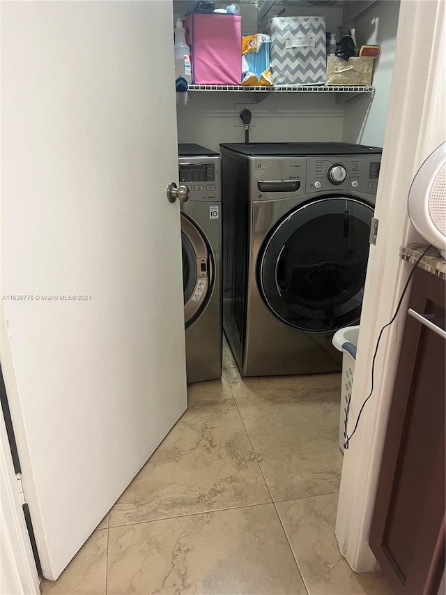 laundry area with washer and dryer and light tile patterned floors