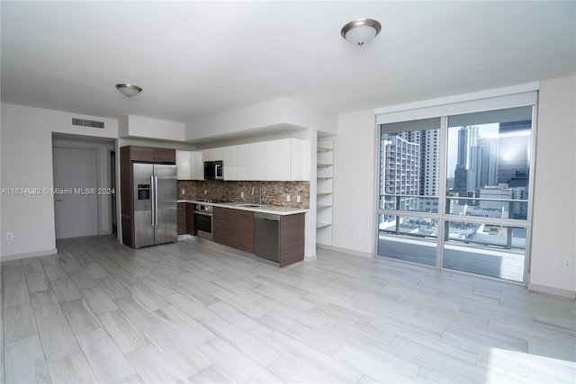 kitchen featuring refrigerator, white cabinetry, backsplash, and dark brown cabinetry