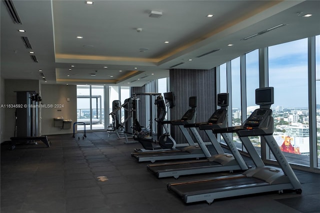 exercise room with a tray ceiling and expansive windows