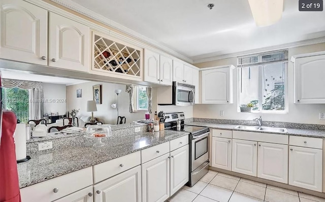 kitchen featuring stainless steel appliances, a sink, ornamental molding, light tile patterned floors, and healthy amount of natural light