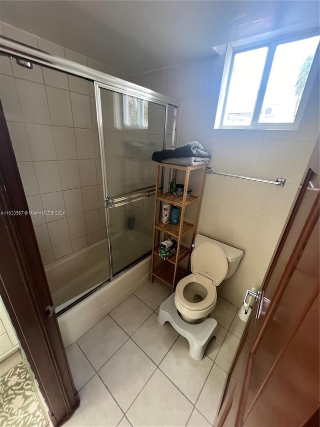 full bath with tile patterned floors, tile walls, a shower with door, and toilet