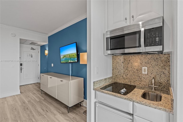 kitchen featuring black electric cooktop, sink, light hardwood / wood-style flooring, tasteful backsplash, and white cabinetry