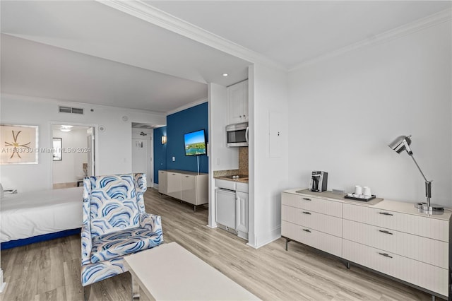 bedroom featuring light hardwood / wood-style floors, ornamental molding, and ensuite bathroom