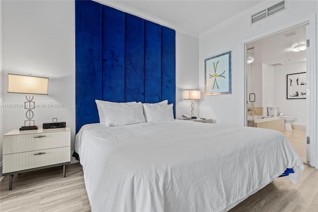 bedroom featuring crown molding, light wood-type flooring, and ensuite bathroom