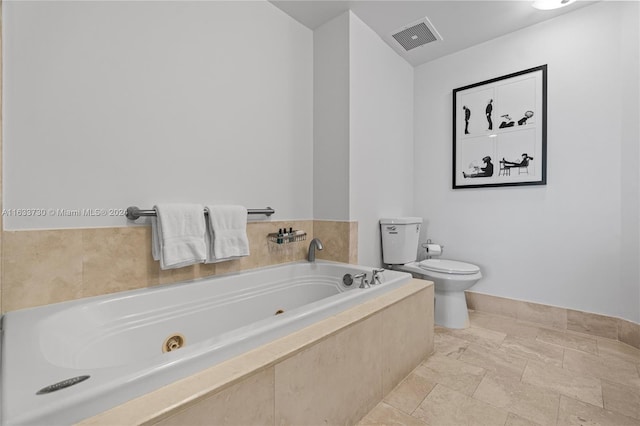 bathroom with tiled bath, toilet, and tile patterned floors