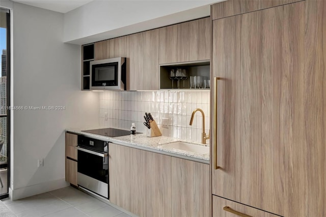 kitchen featuring light brown cabinets, sink, decorative backsplash, appliances with stainless steel finishes, and light stone counters