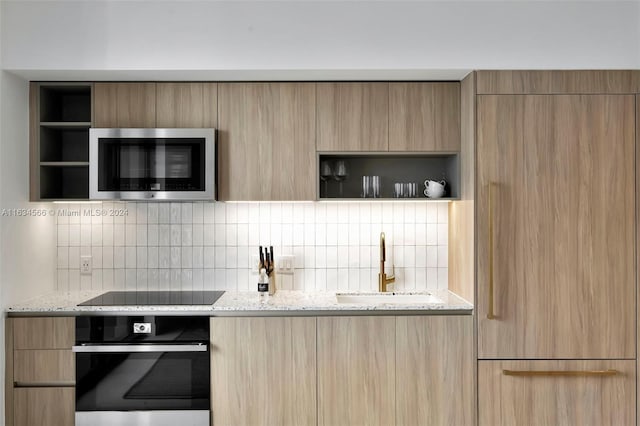 kitchen with light brown cabinetry, light stone counters, sink, and appliances with stainless steel finishes