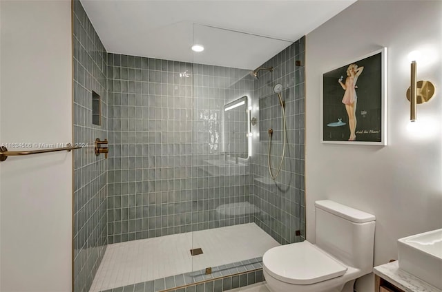 bathroom featuring vanity, toilet, and a tile shower