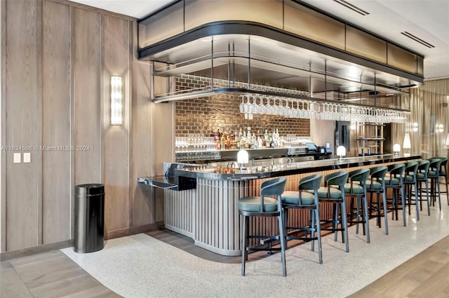 bar with wooden walls and light hardwood / wood-style flooring