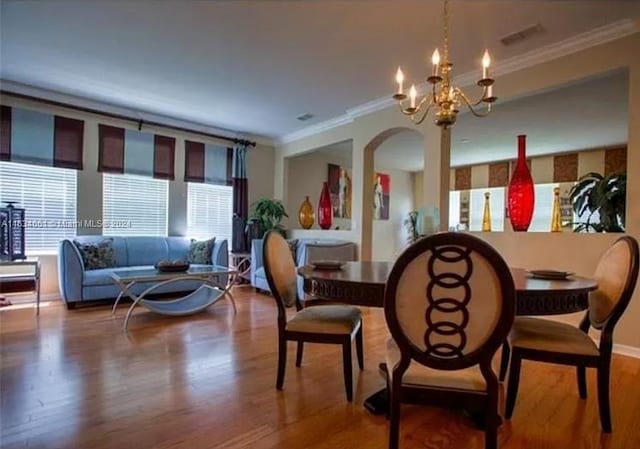 dining area featuring wood-type flooring, a chandelier, and ornamental molding