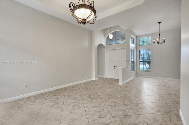 tiled foyer featuring a towering ceiling and a notable chandelier