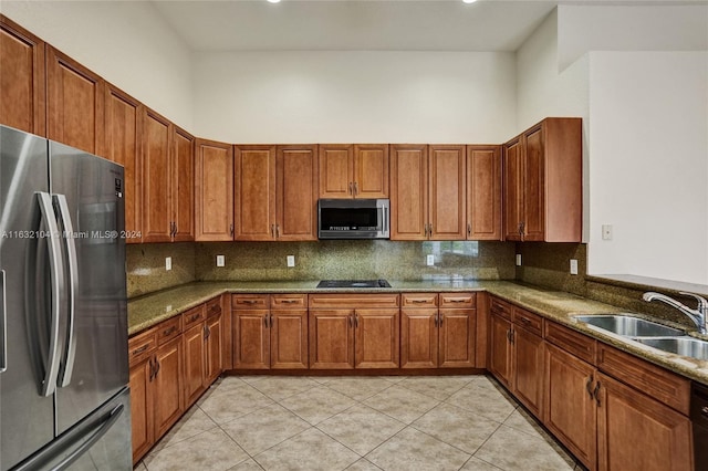 kitchen featuring light stone countertops, sink, decorative backsplash, and black appliances