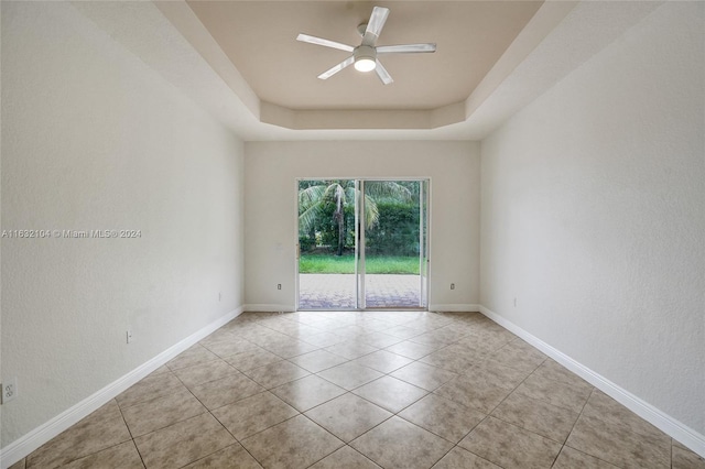 spare room with light tile patterned flooring, ceiling fan, and a tray ceiling