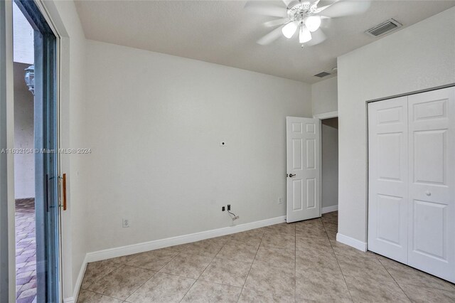 unfurnished bedroom featuring light tile patterned floors, a closet, and ceiling fan