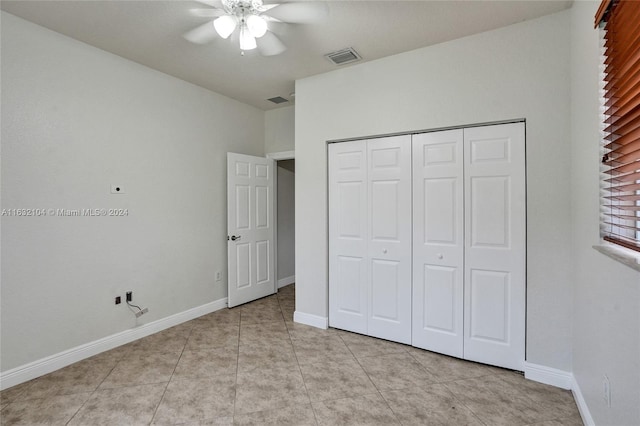 unfurnished bedroom with light tile patterned floors, ceiling fan, and a closet