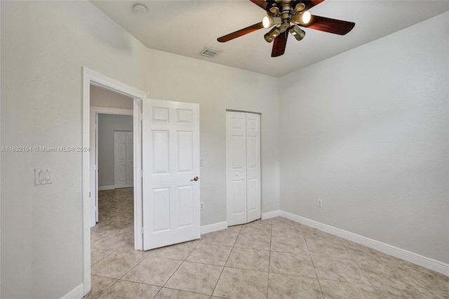 unfurnished bedroom with light tile patterned floors, ceiling fan, and a closet