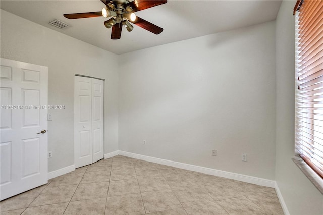 unfurnished bedroom with ceiling fan, a closet, and light tile patterned floors