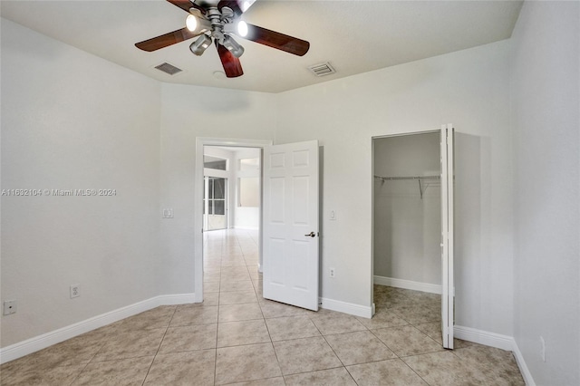 unfurnished bedroom featuring light tile patterned flooring, a walk in closet, ceiling fan, and a closet