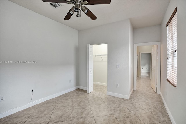 unfurnished bedroom featuring ceiling fan, a walk in closet, a closet, and light tile patterned floors