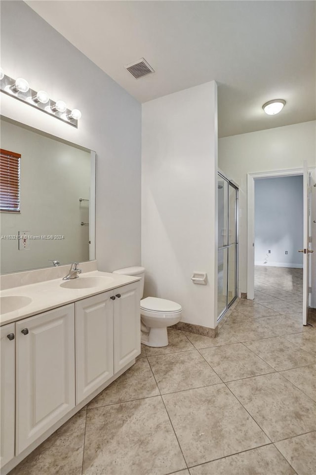 bathroom featuring vanity, a shower with shower door, tile patterned floors, and toilet