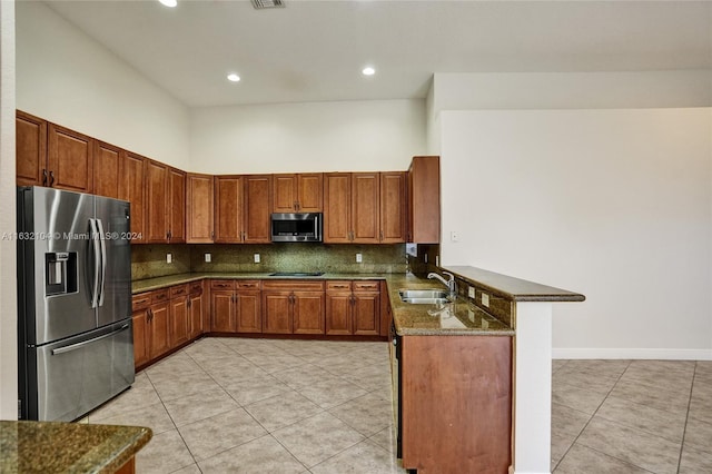 kitchen featuring stainless steel appliances, backsplash, dark stone counters, and kitchen peninsula