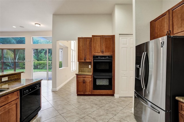 kitchen with stone counters, tasteful backsplash, light tile patterned floors, and black appliances