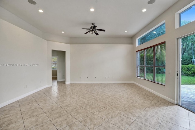 empty room featuring light tile patterned flooring, ceiling fan, and a wealth of natural light